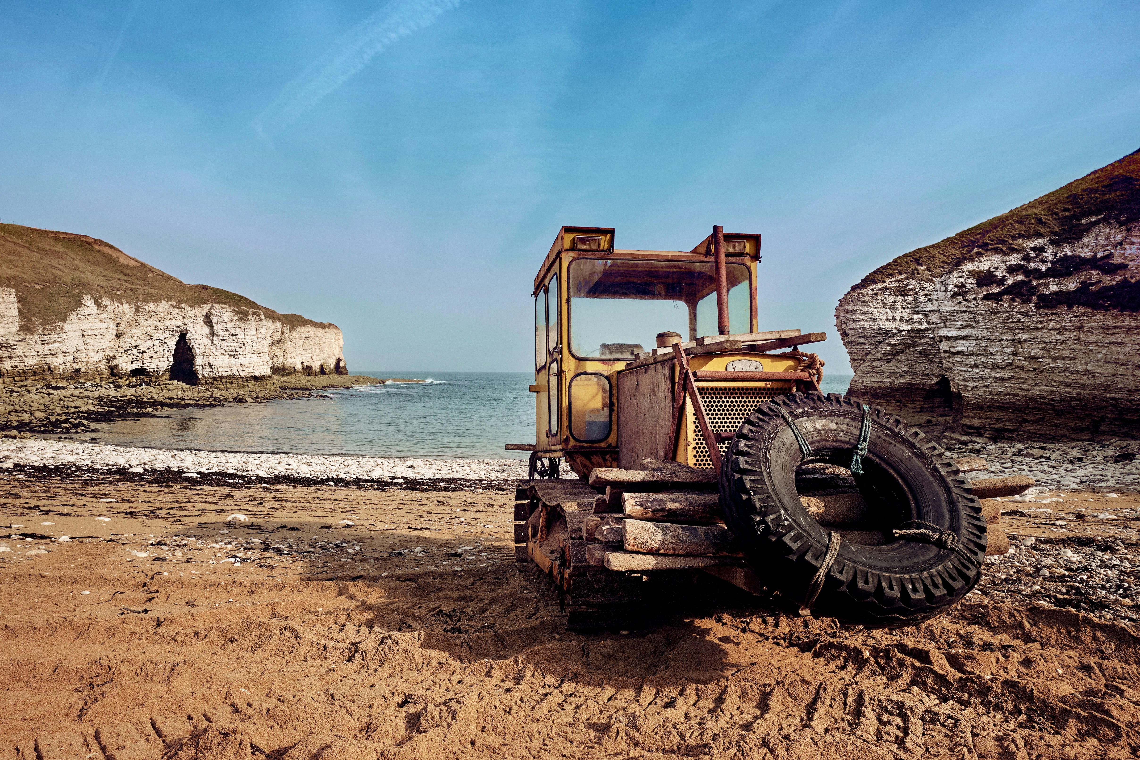 yellow heavy equipment near beach line